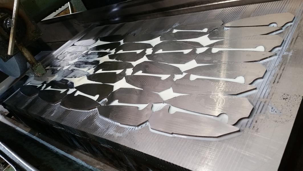 Surface grinding a table load of folding blades to within .0005″ of tolerance.